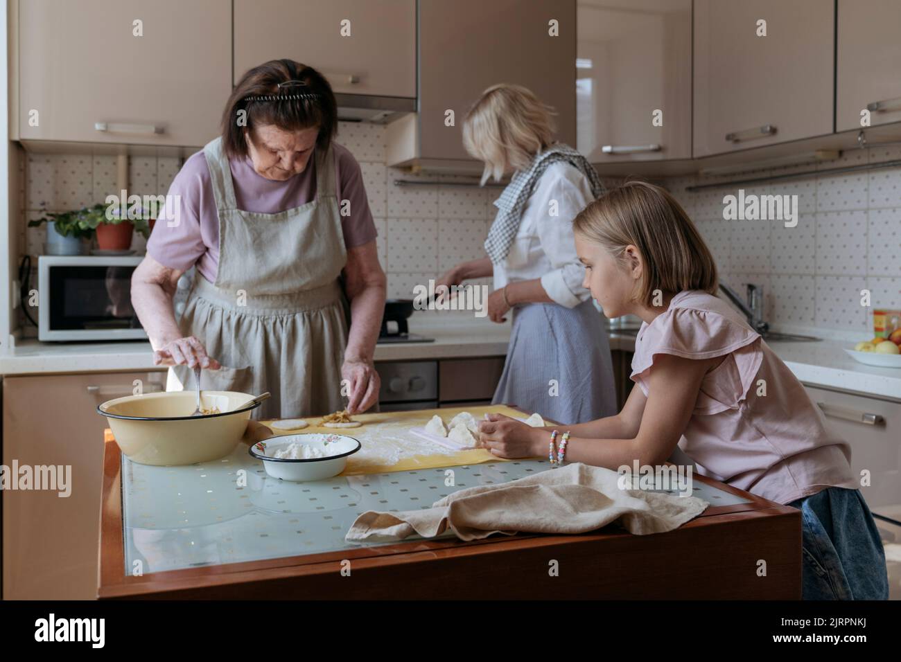 Tre donne in cucina cucinano torte fatte in casa. Foto Stock