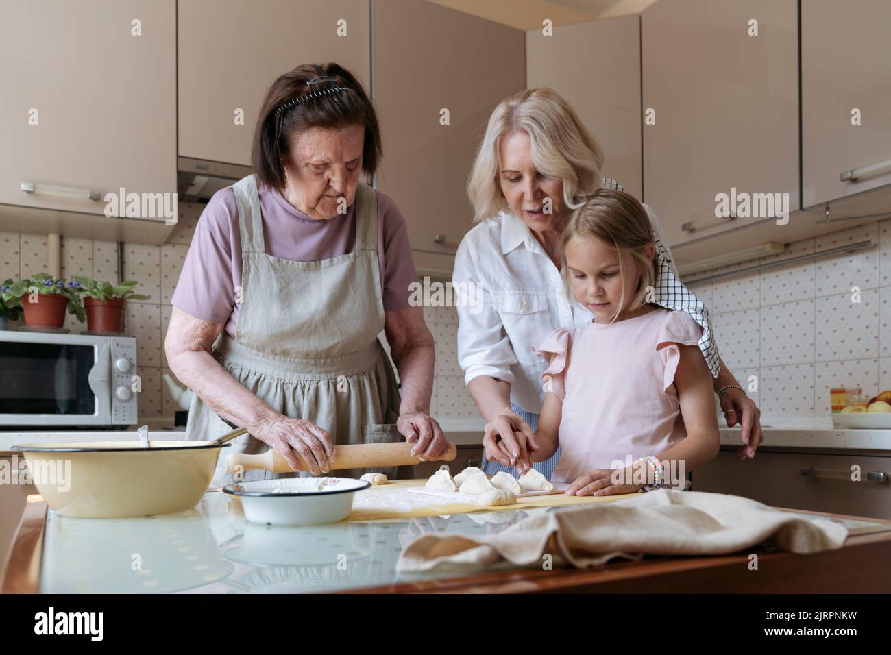 Tre donne in cucina cucinano insieme le torte. Foto Stock