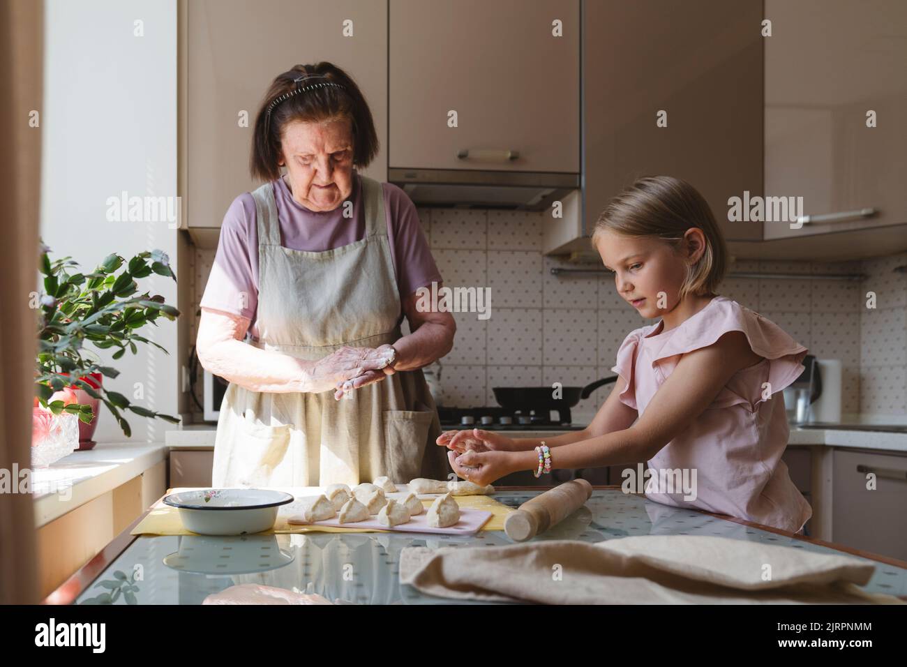 Nonna e sua nipote cucinano torte in cucina. Foto Stock