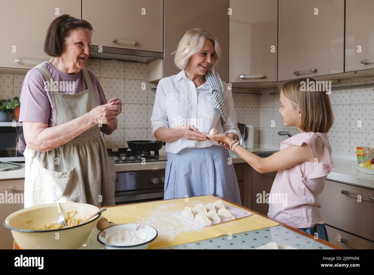 Tre generazioni di donne cucinano torte in cucina. Foto Stock