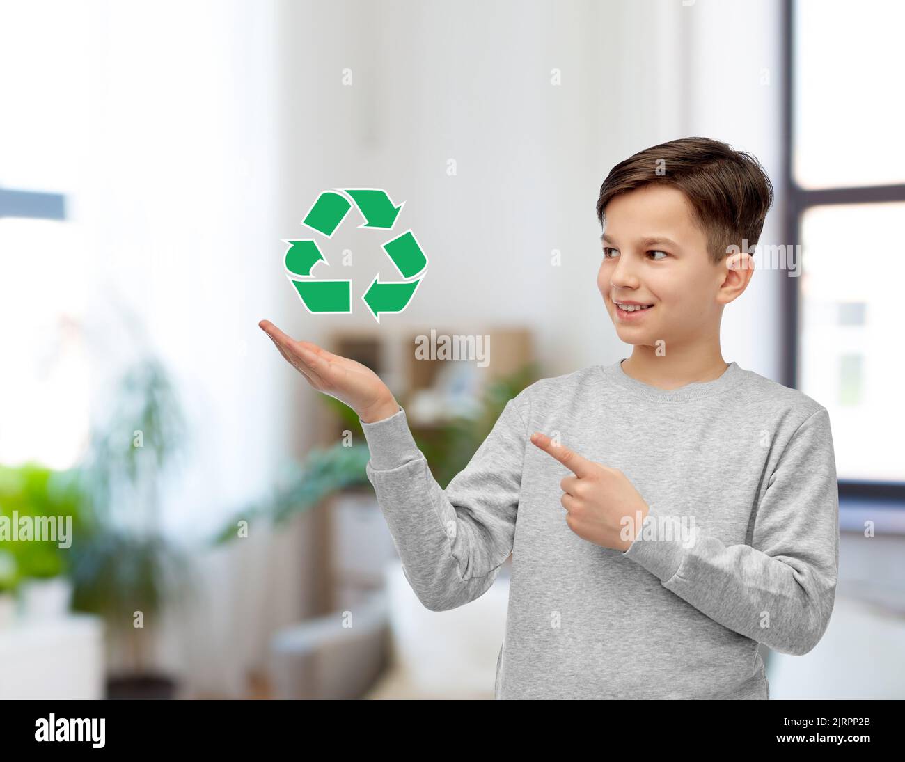 ragazzo sorridente che mostra un cartello verde di riciclaggio Foto Stock