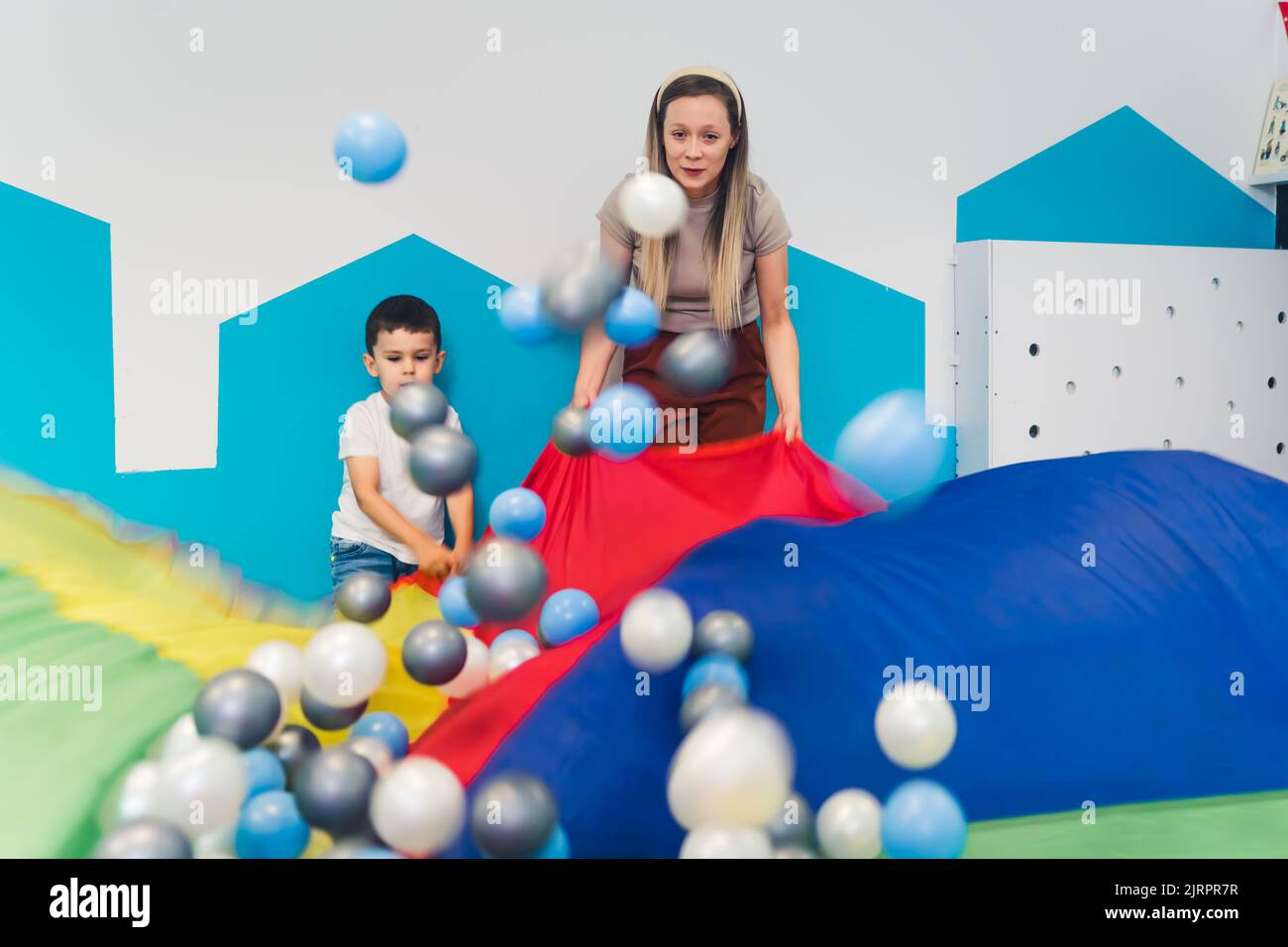 insegnante e bambini che giocano con palline nella sala giochi. Foto di alta qualità Foto Stock