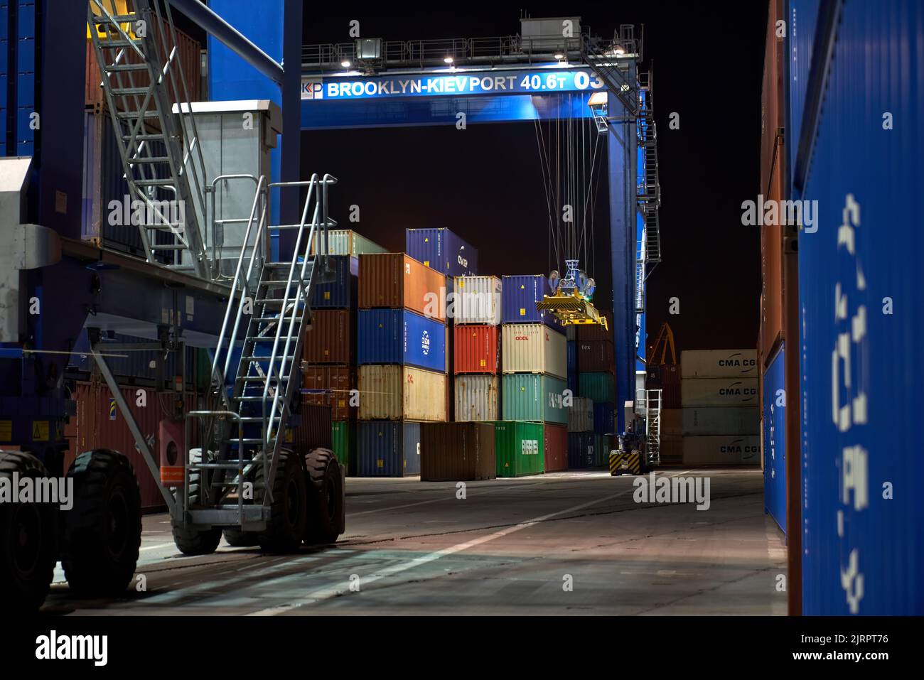 Funzionamento del terminal container di notte. Scarico della nave container di notte. Pile di contenitori al terminal Foto Stock