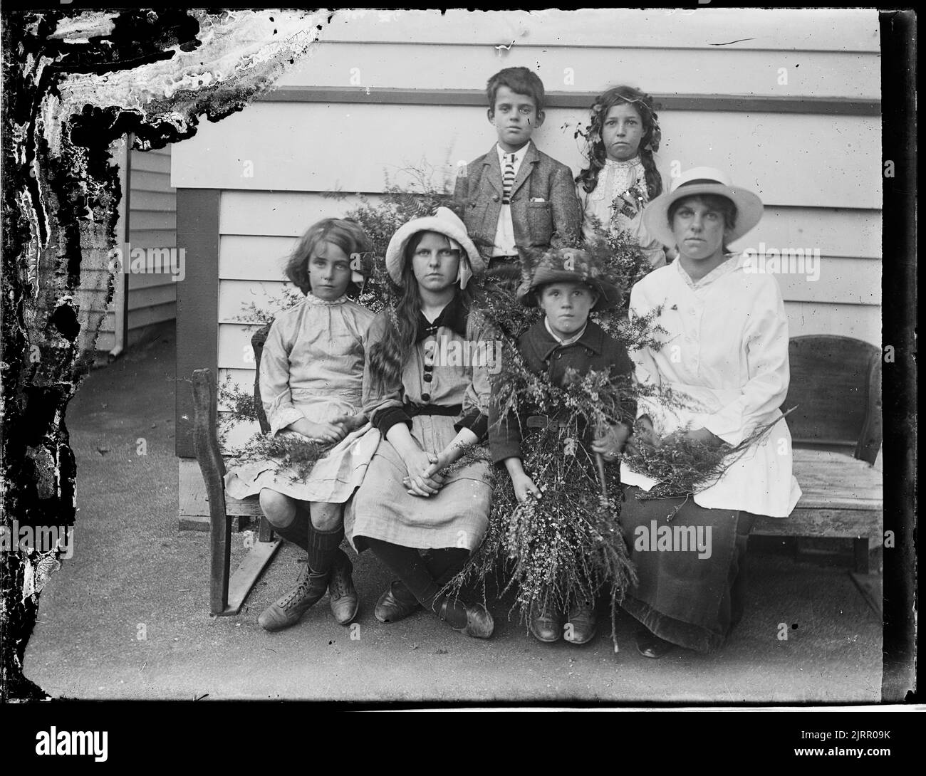 Gruppo di donne e 5 bambini in panchina, con talee di piante, di Crombie e Permin. Foto Stock