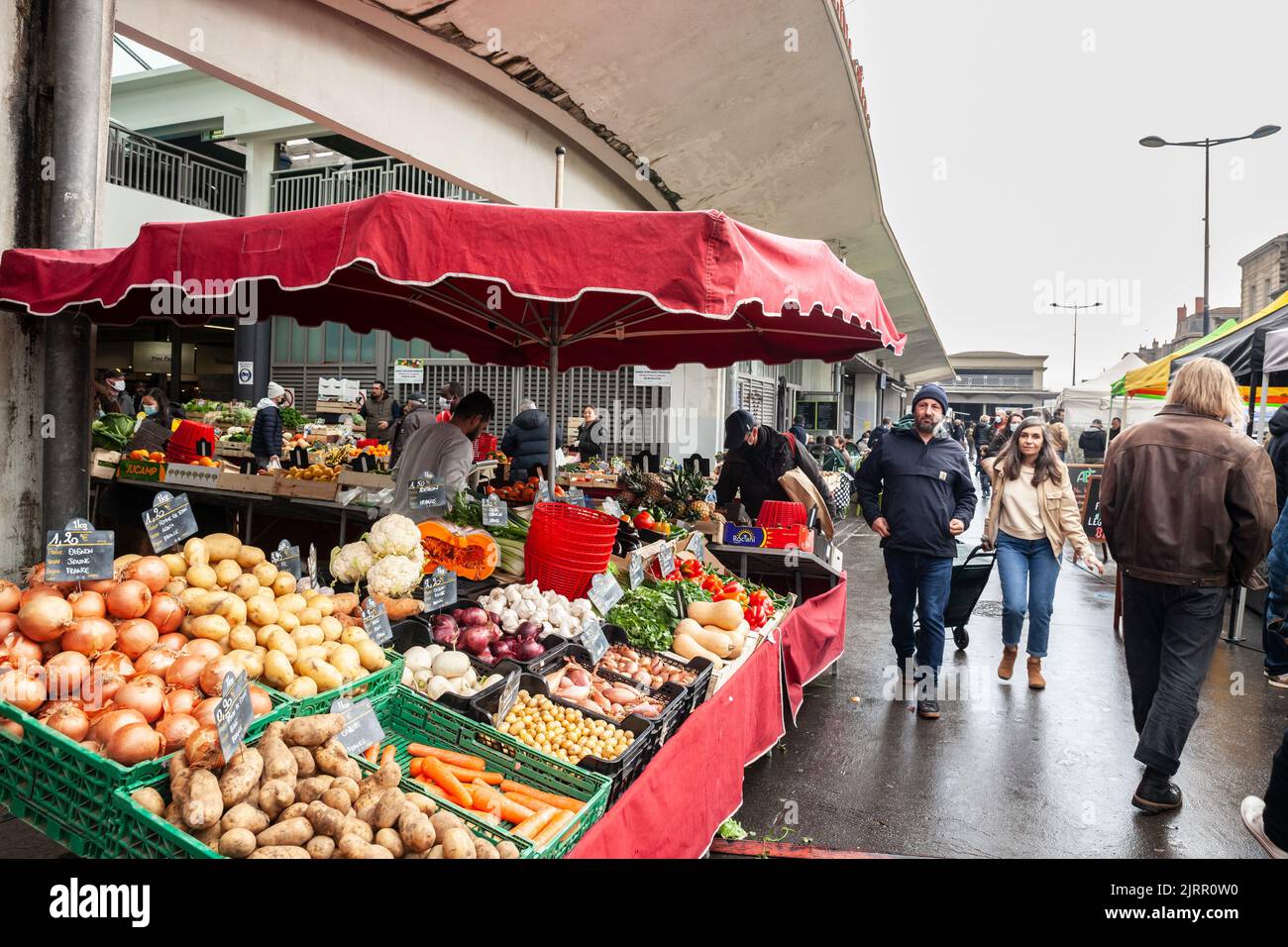 Foto di uno stand del mercato Marche des capucins a Bordeaux, Francia, con una folla di un popolo francese, clienti, acquisto di frutta e verdura. Foto Stock