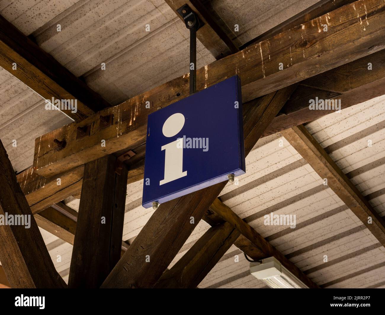 Simbolo delle informazioni presso un edificio della stazione ferroviaria. Lettera i su una lastra metallica blu appesa al tetto di un edificio. Punto informativo per i turisti. Foto Stock