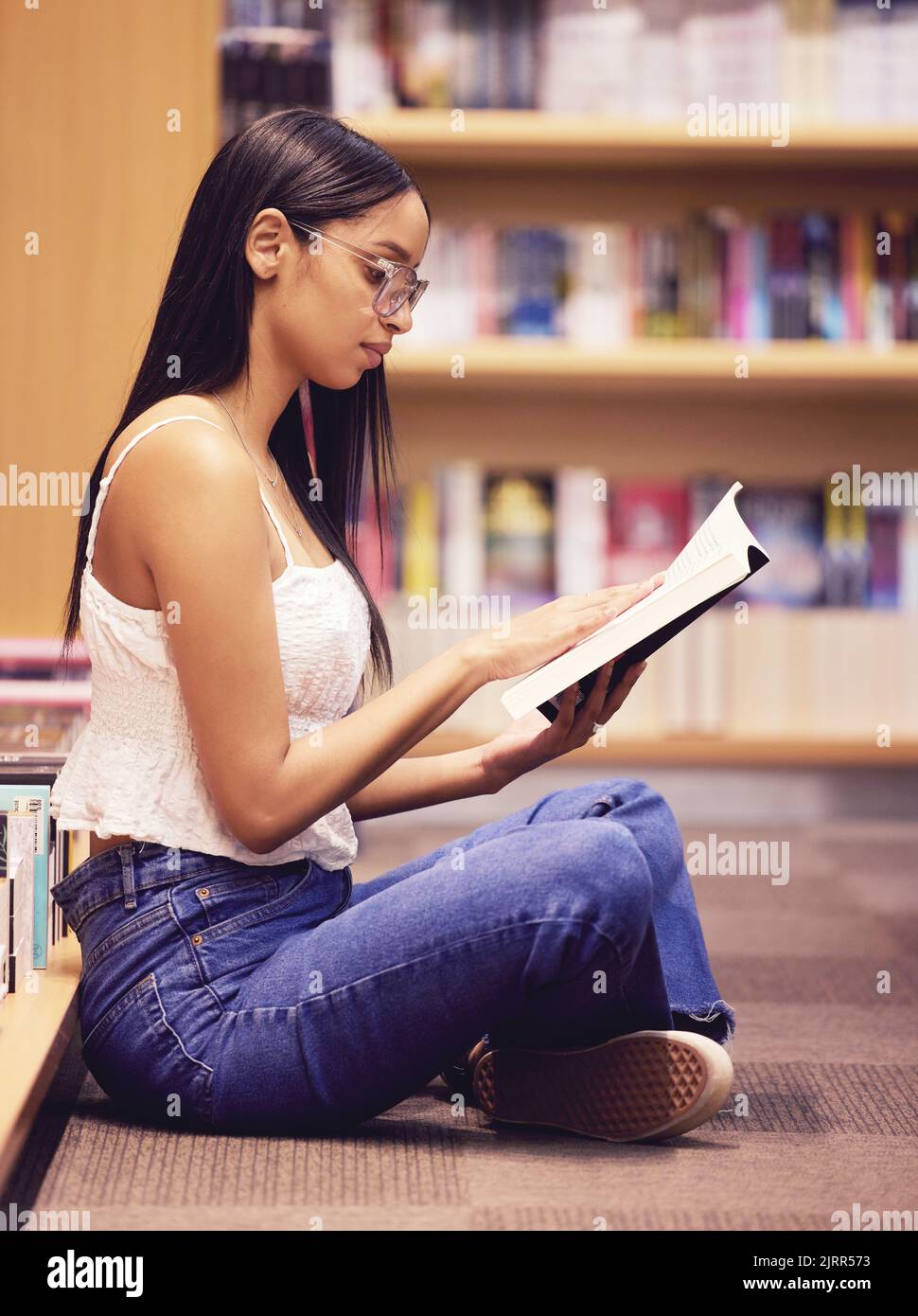 Studenti universitari che leggono libri di biblioteca al piano terra per l'istruzione, lo studio e l'apprendimento del campus. Giovane donna nerd in libreria che studia per Foto Stock