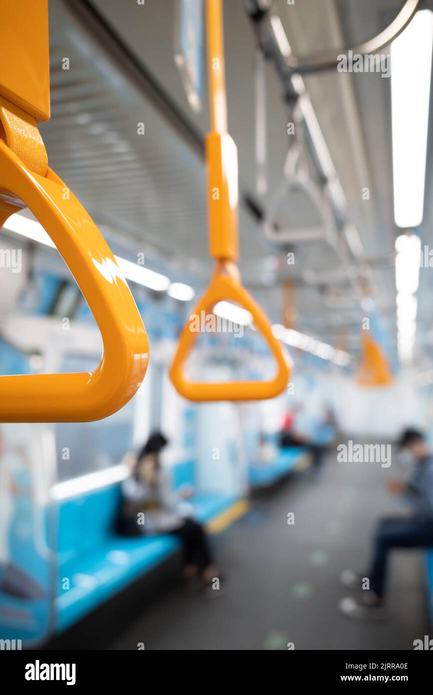Primo piano dell'impugnatura gialla su un treno della metropolitana con il passeggero sullo sfondo Foto Stock