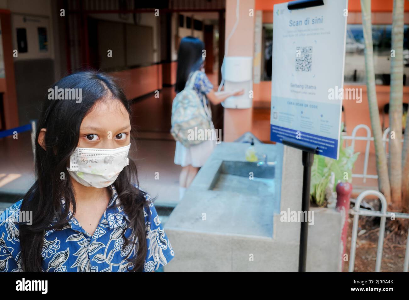 Studentessa elementare del sud-est asiatico con maschera facciale di nuovo a scuola dopo una pandemia covida Foto Stock