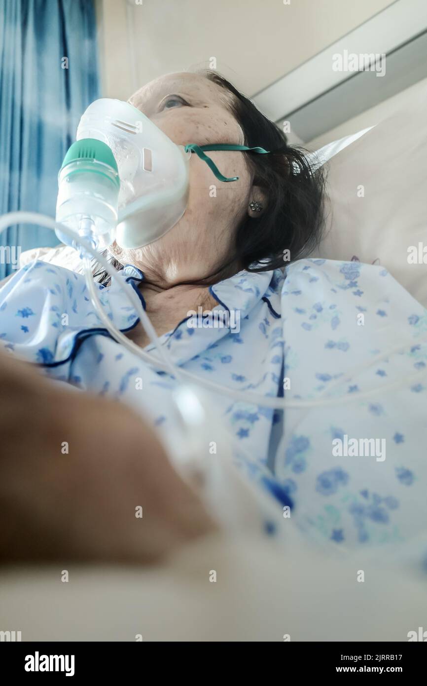 Sudest asiatico donna anziano in trattamento in ospedale utilizzando nebulizzatore Foto Stock