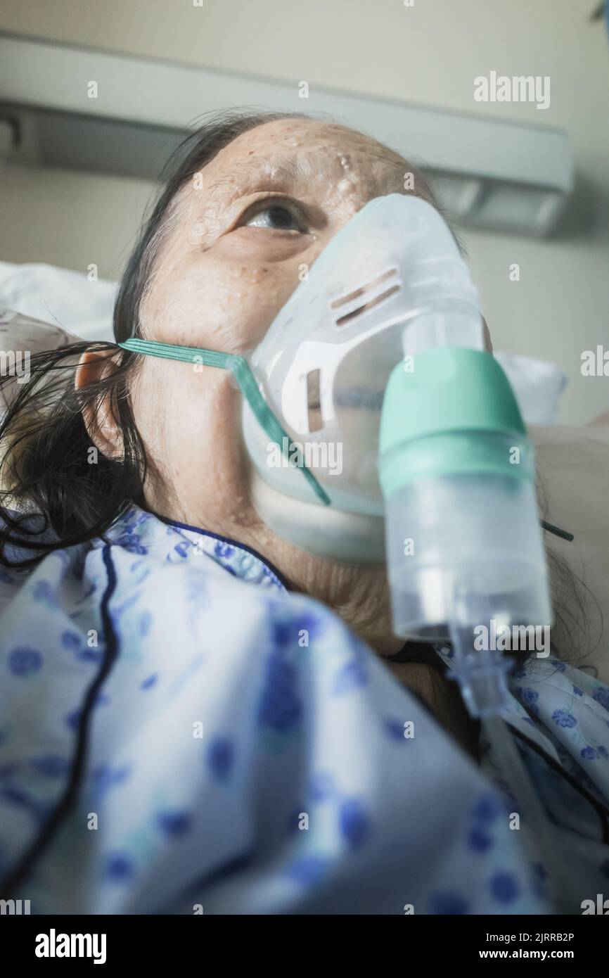 Sudest asiatico donna anziana in trattamento in ospedale utilizzando nebulizzatore Foto Stock