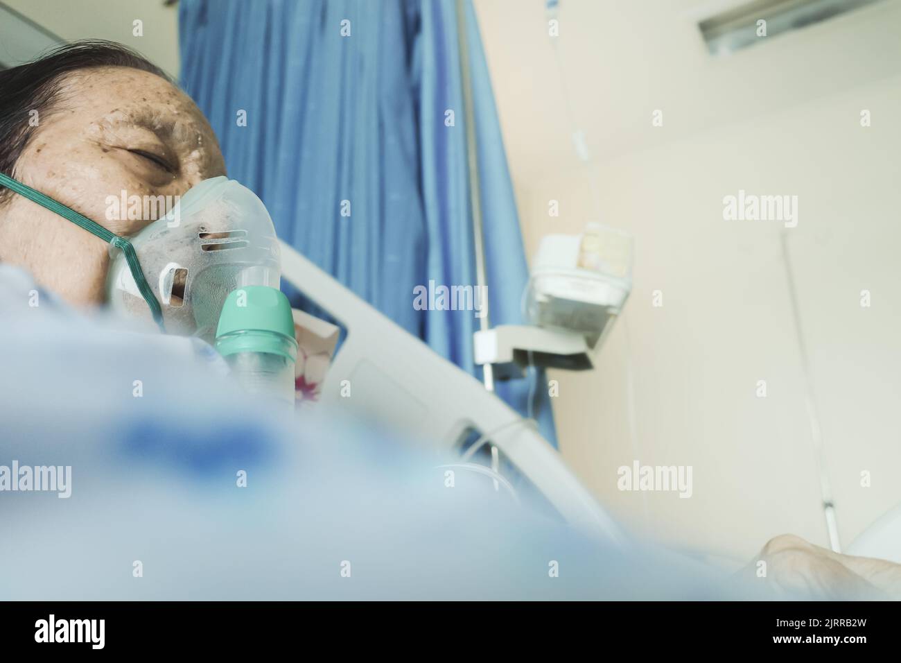 Sudest asiatico donna anziana in trattamento in ospedale utilizzando nebulizzatore Foto Stock