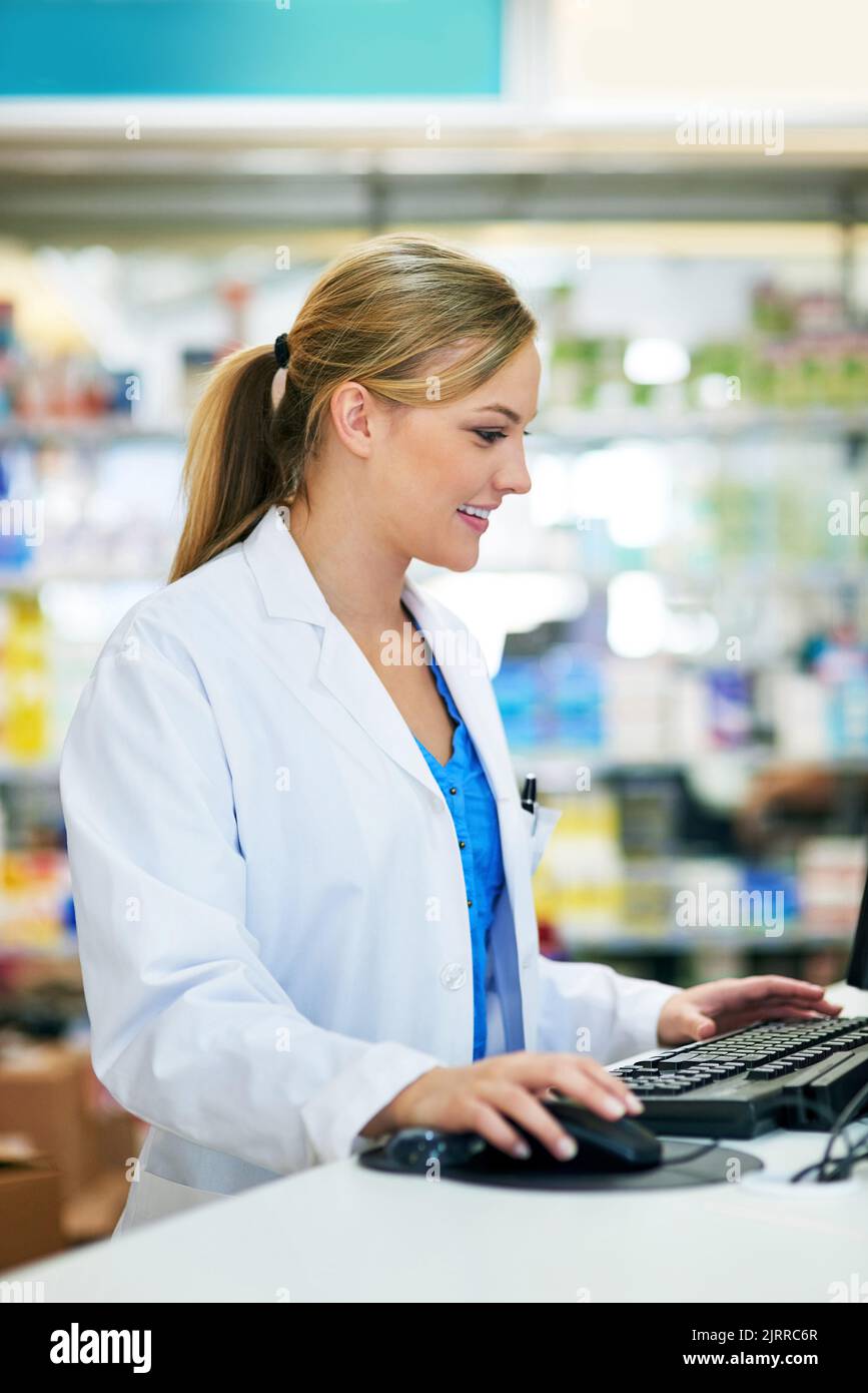 Invio di una conferma via e-mail per la prescrizione dei clienti. Giovane farmacista che utilizza un computer al banco cassa. Foto Stock