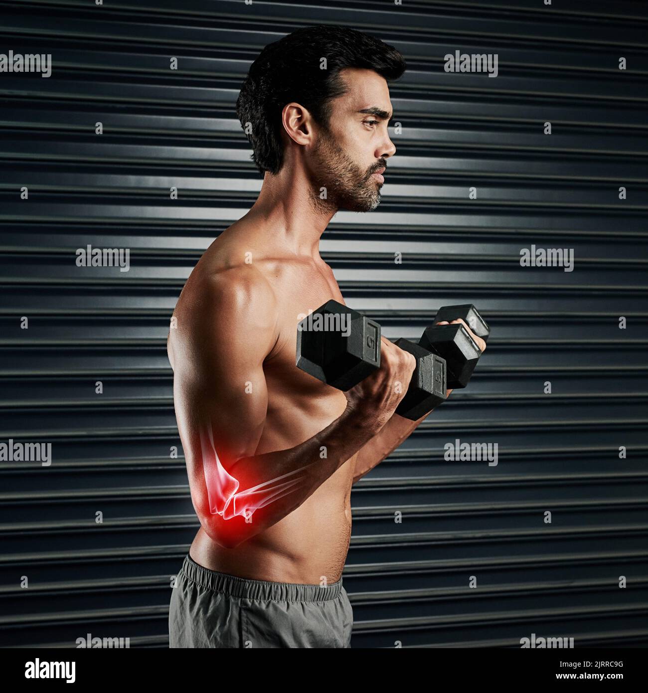 Spingendosi verso il punto di lesione. Studio shot di un giovane muscolare che solleva manubri con cgi evidenziando il gomito. Foto Stock
