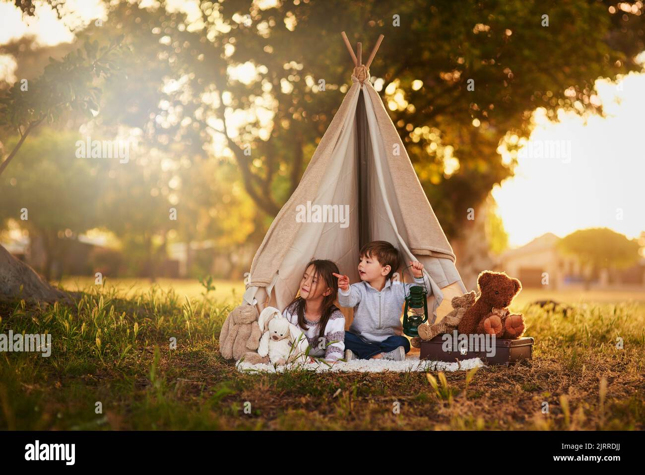 Dovremmo andare a esplorare là. Due piccoli fratelli carini che giocano insieme in un teepee fuori. Foto Stock