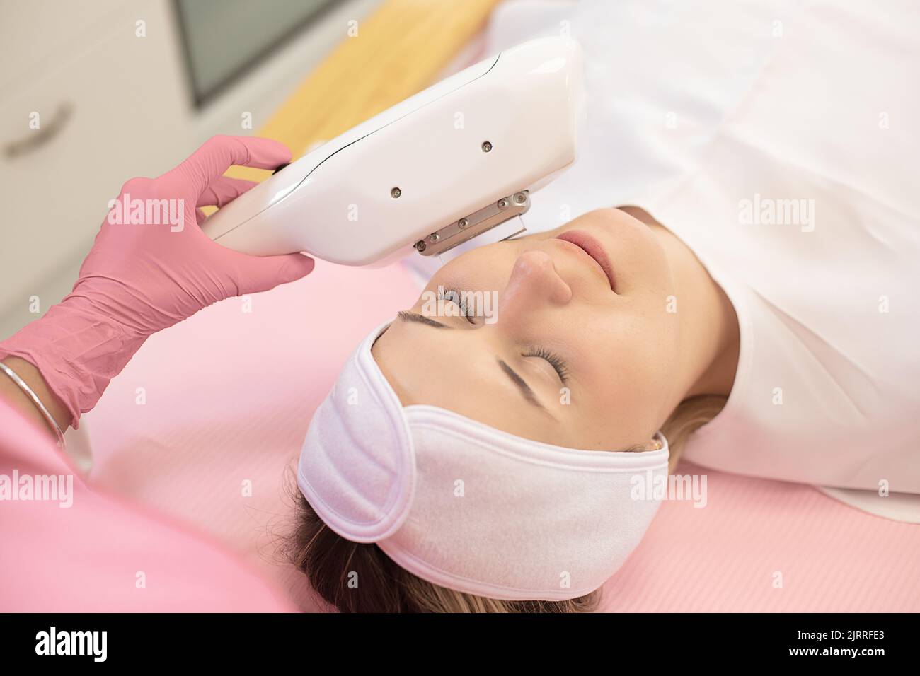 Vista dall'alto della giovane donna sdraiata con gli occhi chiusi, ringiovanita, rassodante della pelle, trattamento di pulizia profonda con laser. Foto Stock