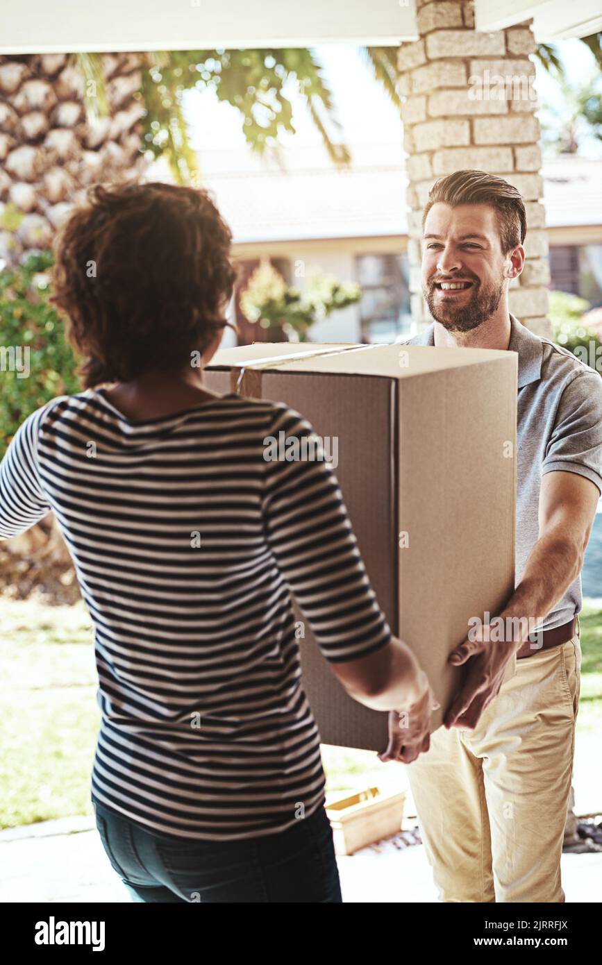 Un servizio che mantiene i suoi clienti ordinando di più. Un addetto alla consegna che effettua una consegna a un cliente a casa sua. Foto Stock