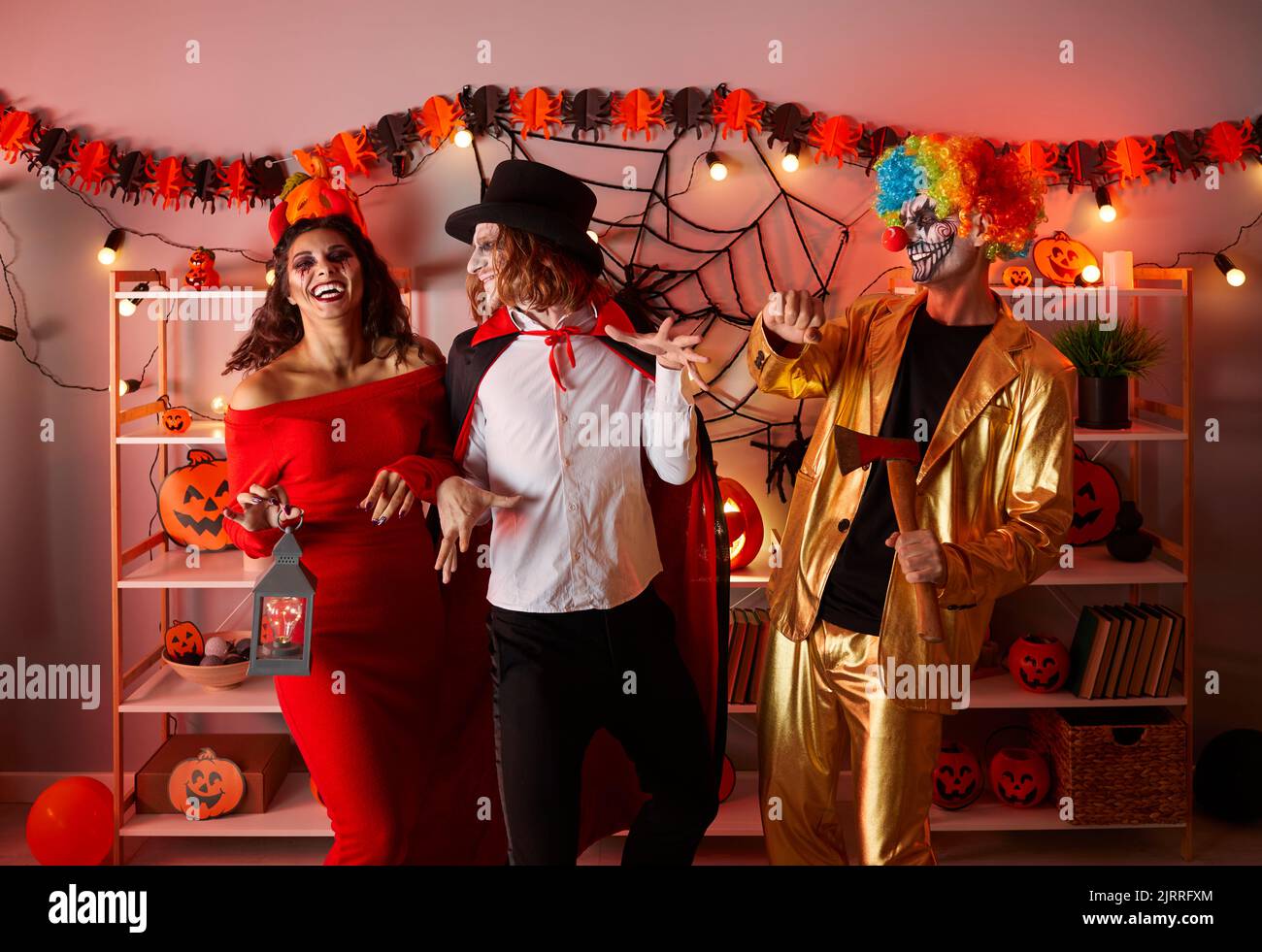 Amici che ballano, ridono e che si divertono a festa in costume di Halloween adulto a casa Foto Stock