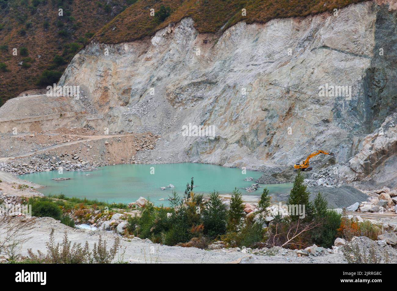escavatore in una cava mineraria con un lago. industria mineraria Foto Stock