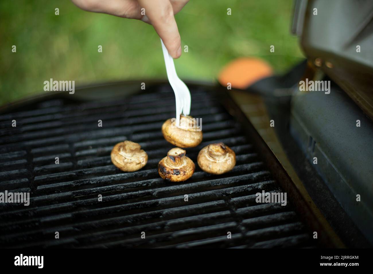 I funghi vengono grigliati. Dettagli picnic. Cibo su grata di acciaio. Cucina in estate. Foto Stock