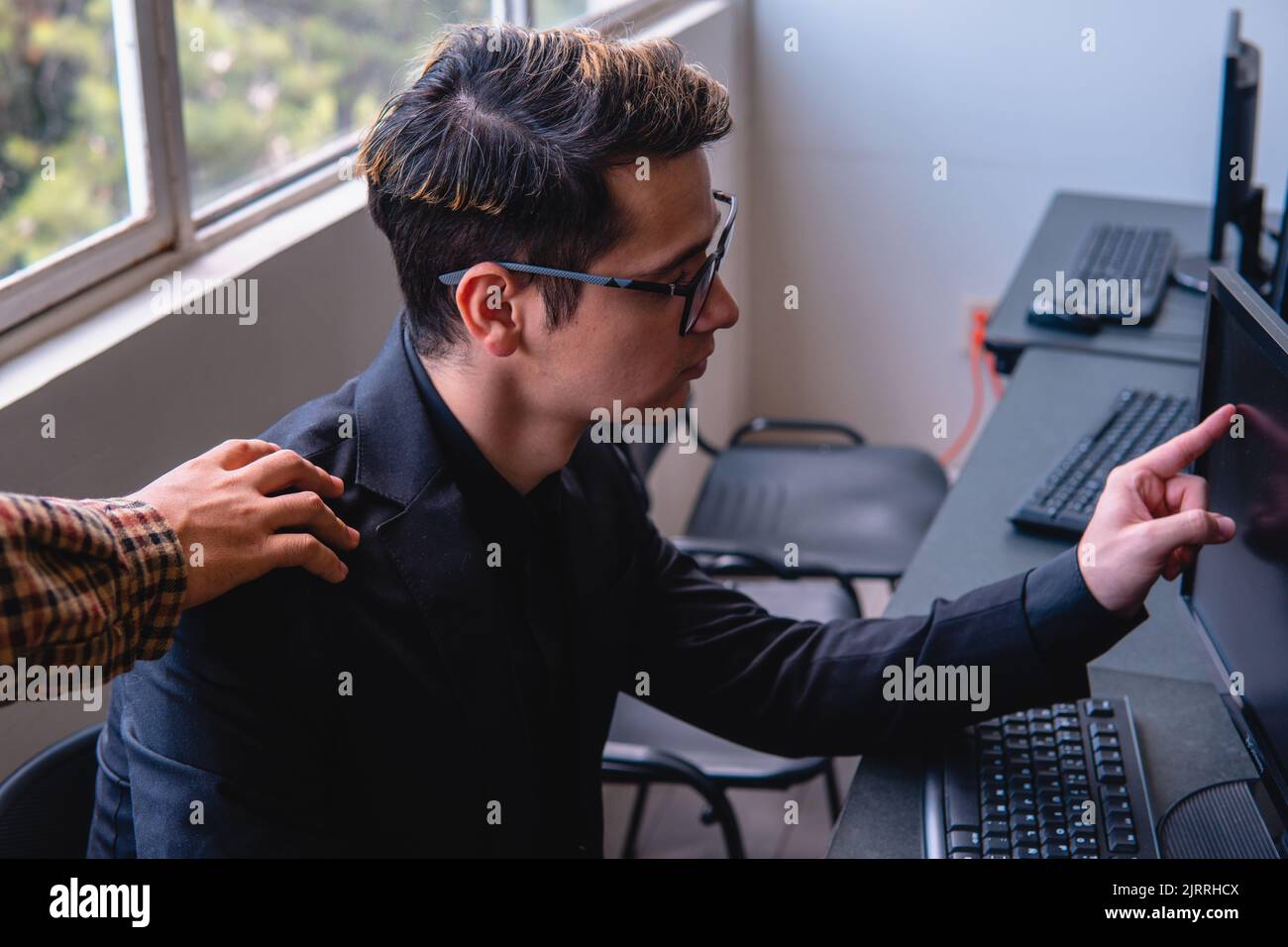 L'uomo che lavora al suo computer in ufficio e il suo capo lo afferra per la spalla. Uomo biondo caucasico al computer che punta allo schermo per il suo capo di vedere qualcosa. Uomo d'ufficio. Foto di alta qualità Foto Stock