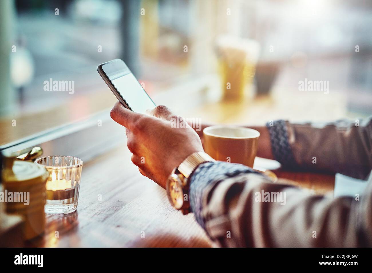 Caffè e wifi gratuito. Ripresa di un giovane che legge un messaggio di testo mentre si siede al bancone in un bar. Foto Stock
