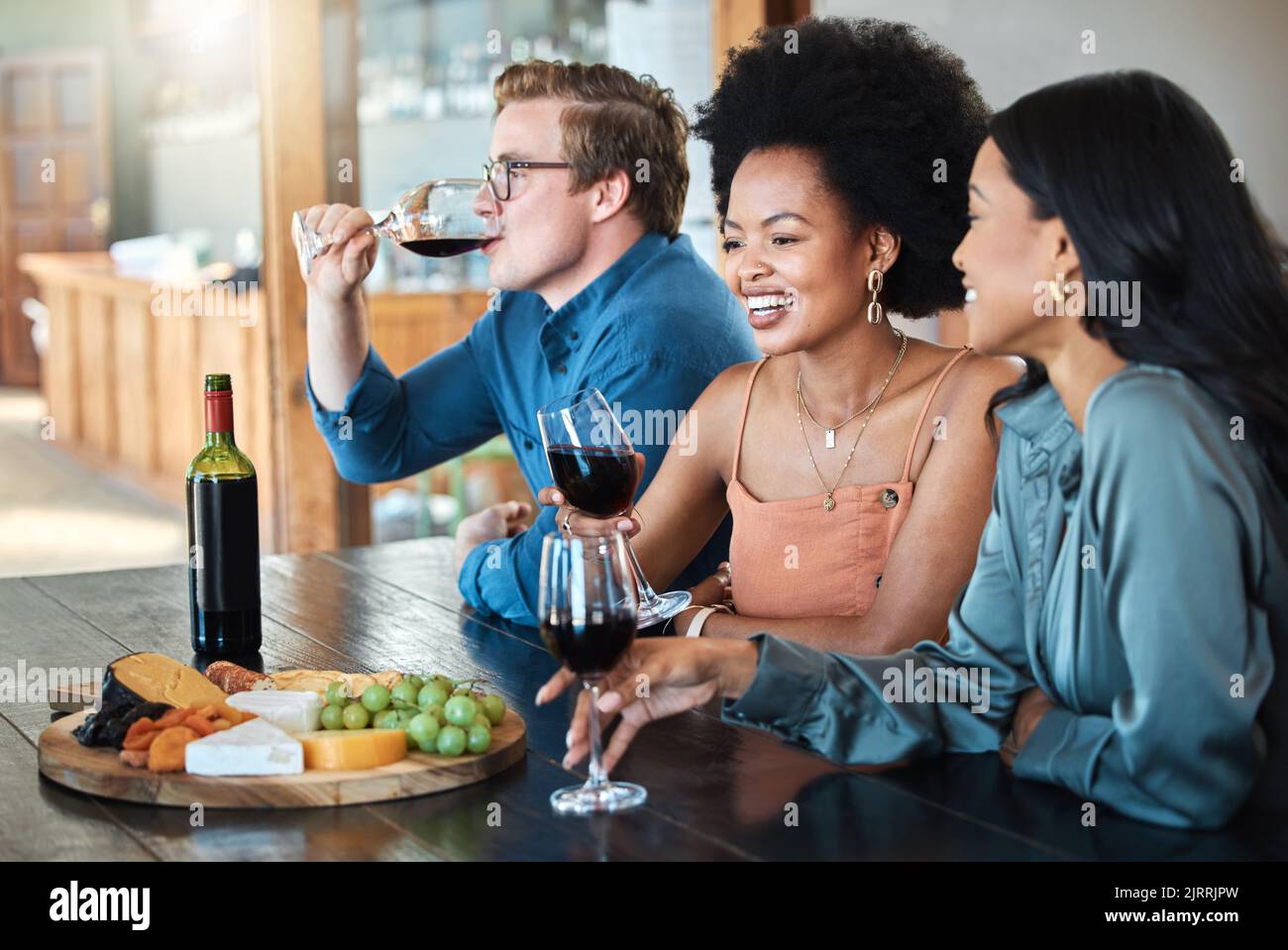Festa del vino, amici e felice degustazione di lusso con frutta biologica sana con formaggio e alcol su un tavolo da pranzo. Sorriso, diversità e giovane gruppo di Foto Stock