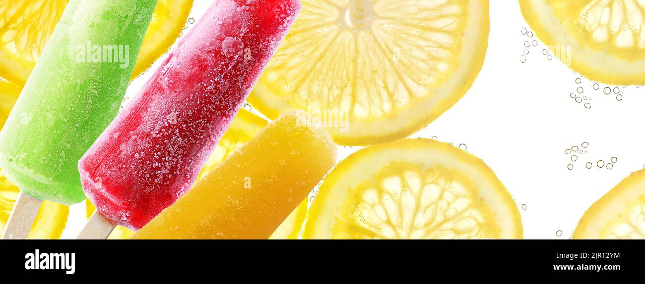 Il popsicle luminoso si attacca sulle fette di limone in fondo all'acqua di soda Foto Stock
