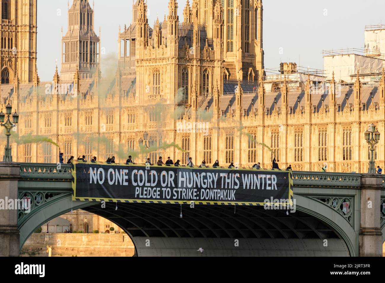 Londra, Regno Unito. 26th ago, 2022. Gli attivisti non paganti hanno lasciato cadere una bandiera che legge 'Nessuno freddo o affamato questo inverno' da Westminster Bridge per protestare contro il nuovo limite del prezzo dell'energia annunciato da Ofgem allo stesso tempo. Credit: Andrea Domeniconi/Alamy Live News Foto Stock