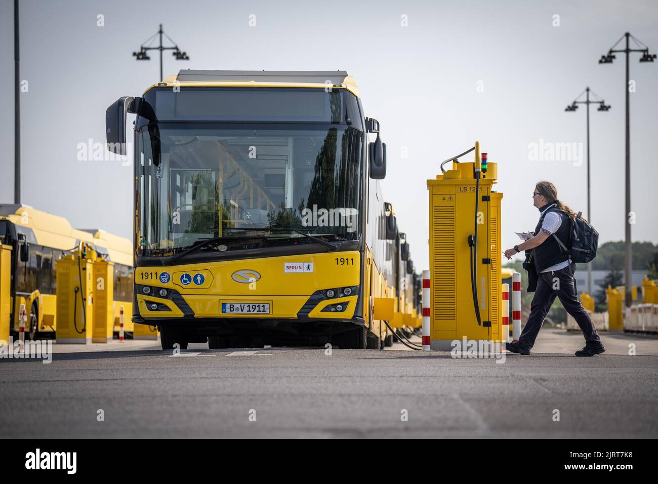 Berlino, Germania. 26th ago, 2022. Gli e-bus del produttore polacco Solaris sono parcheggiati presso i punti di ricarica dell'autorità di trasporto di Berlino presso il deposito BVG Indira-Gandhi-Straße mentre un autista cammina verso il suo veicolo. Credit: Michael Kappeler/dpa/Alamy Live News Foto Stock