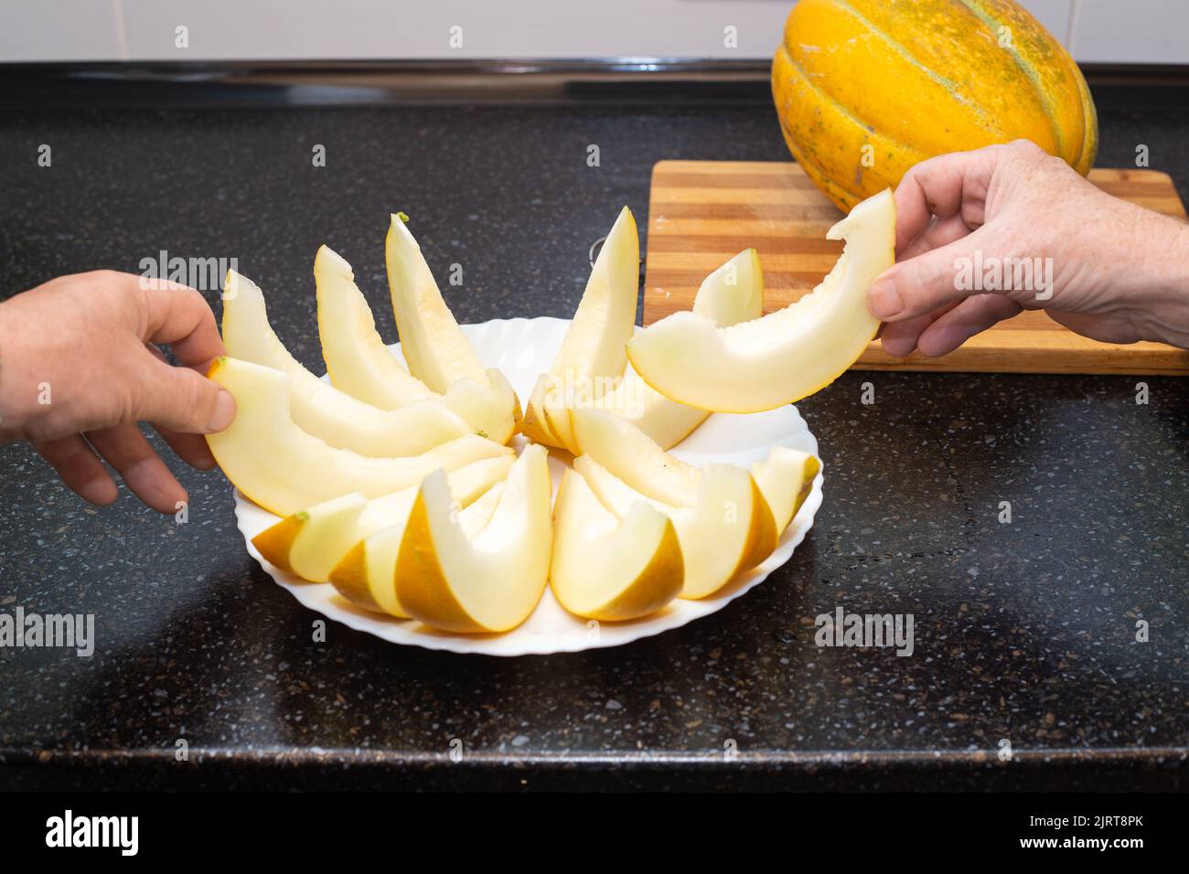 Le persone prendono fette di melone maturo succosa affettate dal piatto con le mani. Delizioso cibo sano. Foto Stock