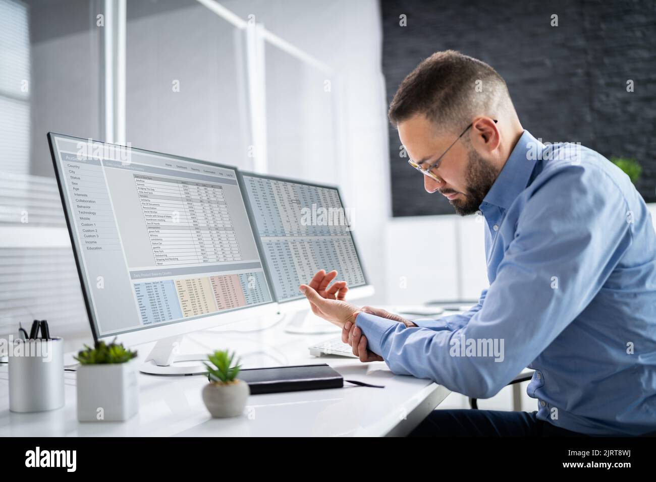 Giovane uomo con dolore al nervo pizzicato alla scrivania dell'ufficio Foto Stock