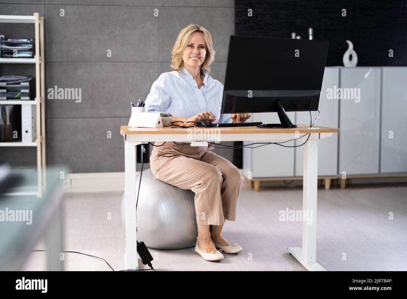 Correggere la postura alla scrivania in ufficio usando la sfera di idoneità Foto Stock