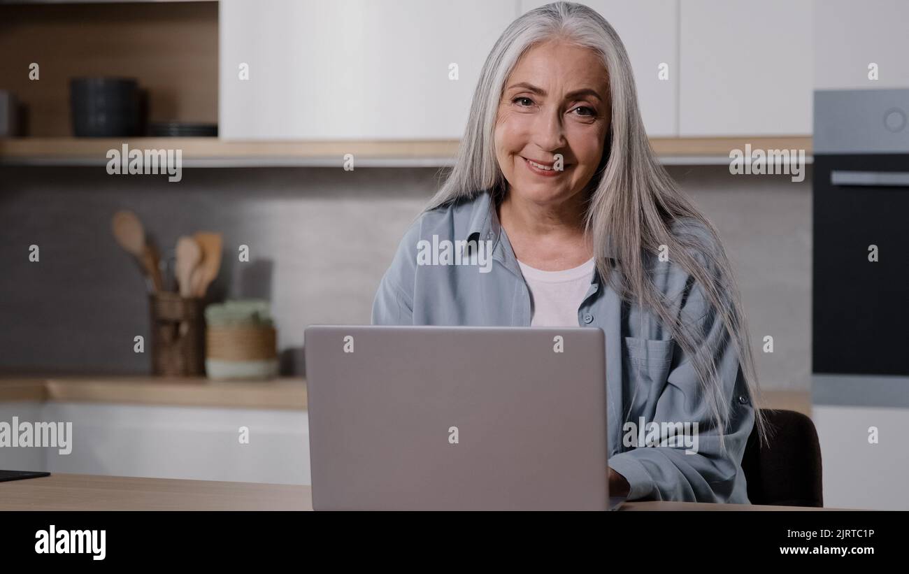 Maturo alla moda caucasica vecchia donna d'affari insegnante domestico anziana casalinga granny digitando sulla tastiera laptop in cucina uso casa internet check Foto Stock