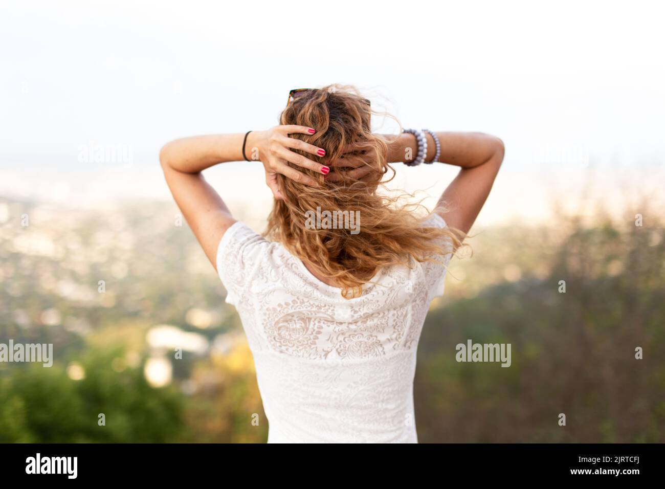 Giovane donna arrossata con capelli ricci che tiene la testa con mal di testa outtoors Foto Stock