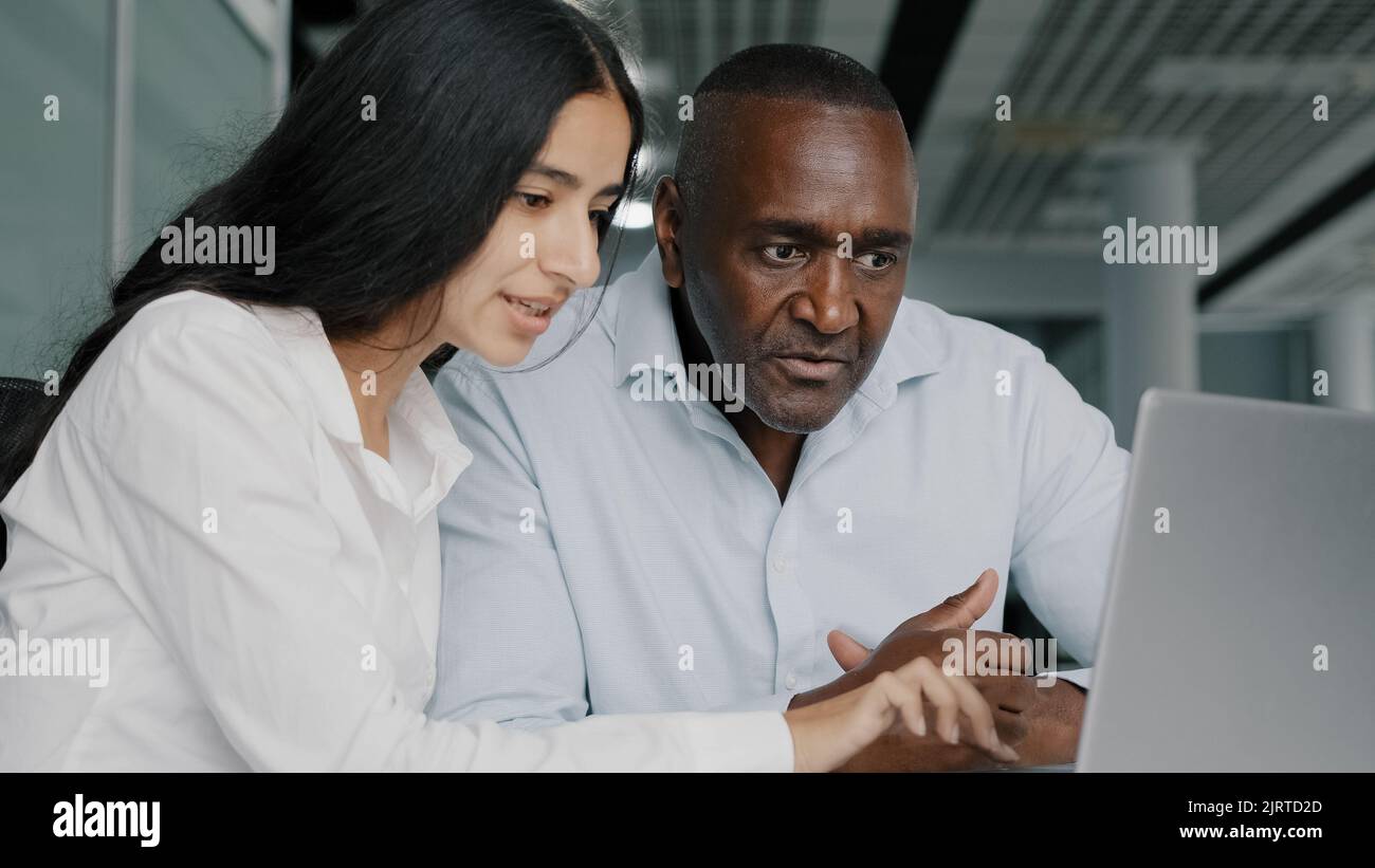 Uomo d'affari maschio africano avvocato consulente finanziario agente discutere progetto internet arabo giovane femmina tirocinante consultare il cliente spiegando l'assicurazione a. Foto Stock