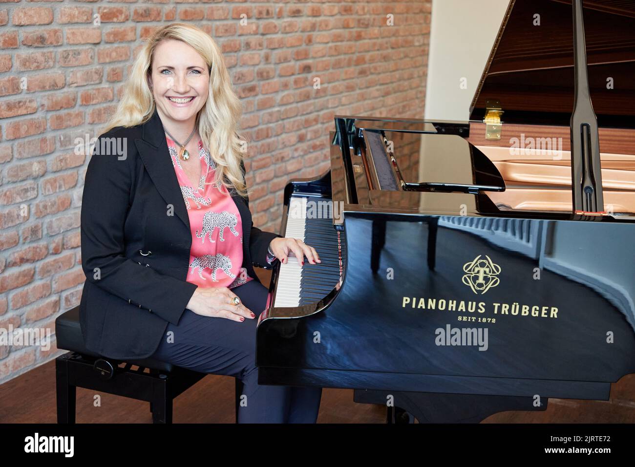 25 agosto 2022, Amburgo: Yvonne Trübger, proprietario, si siede a un pianoforte a coda durante una sessione fotografica per celebrare il 150th° anniversario di Pianohaus Trübger. La piano house è una delle ultime case pianistiche che non rappresenta un solo marchio. (A dpa 'Pianohaus Trübger dà via 15 pianoforti per 150th anniversario') Foto: Georg Wendt/dpa Foto Stock