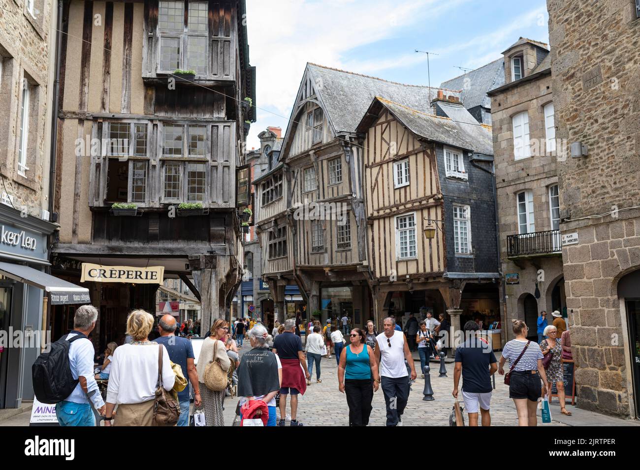 Folla di turisti a piedi una strada commerciale al centro della città medievale di Dinan, Bretagna, Francia Foto Stock