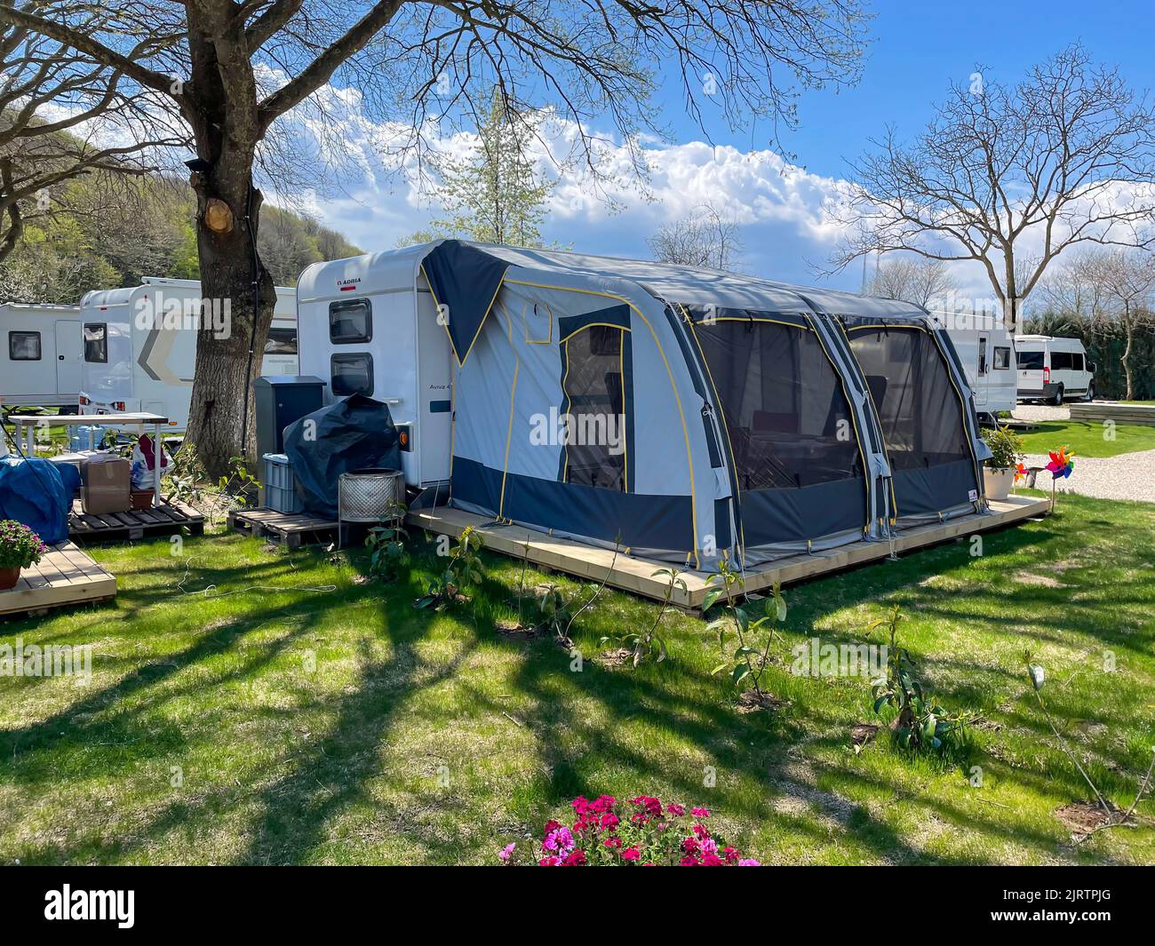 Una tenda di fronte ad un rimorchio di corsa ad un campeggio, campeggio del caravan, campeggio di distensione, parcheggio del rimorchio, campeggio estivo Foto Stock