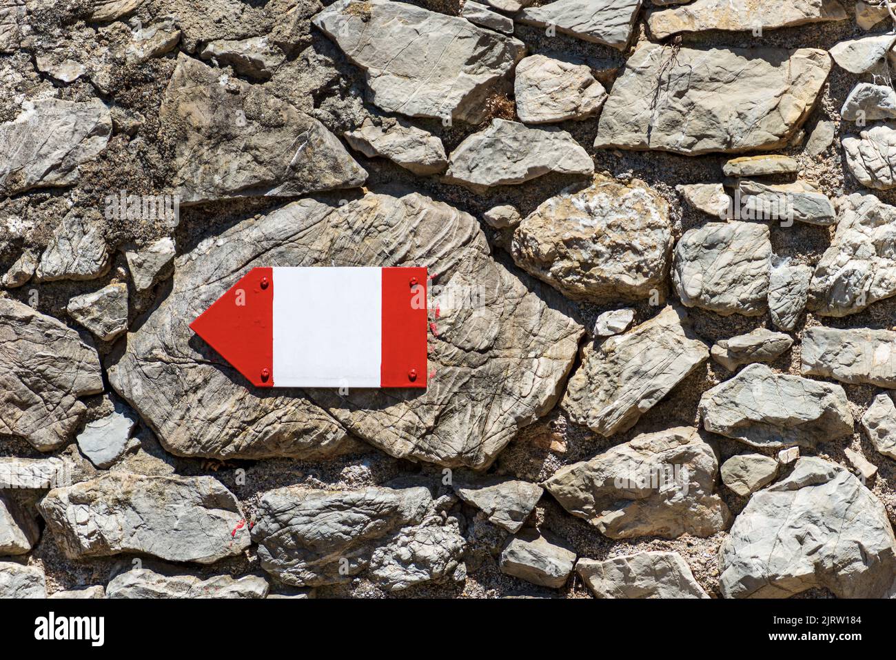 Primo piano di un cartello direzionale rosso e bianco con spazio copia su un muro di pietra, sentiero in Liguria, cinque Terre, Italia, Europa. Foto Stock
