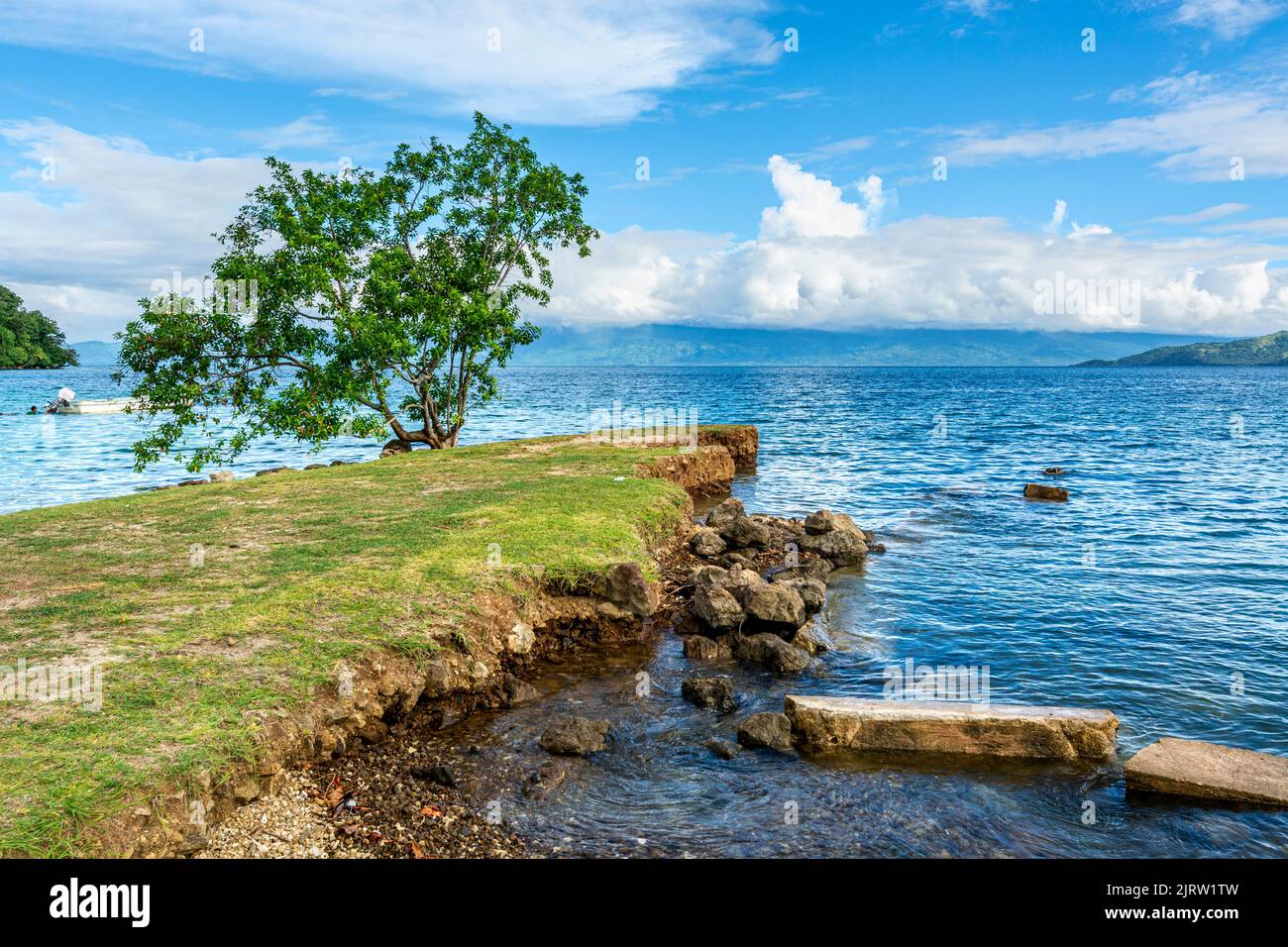 Una piccola isola con una vista erbosa di un bel cielo blu e dell'oceano nelle Fiji tropicali Foto Stock