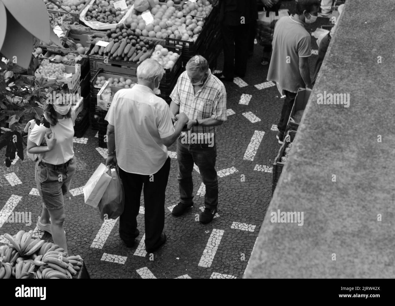 Un colpo in scala di grigi delle persone che fanno transazioni in un mercato locale Foto Stock