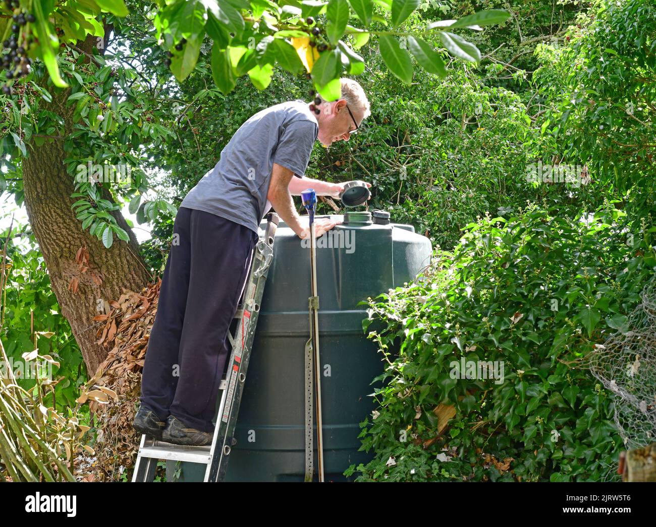 uomo che controlla il livello del serbatoio dell'olio combustibile domestico nel giardino regno unito Foto Stock