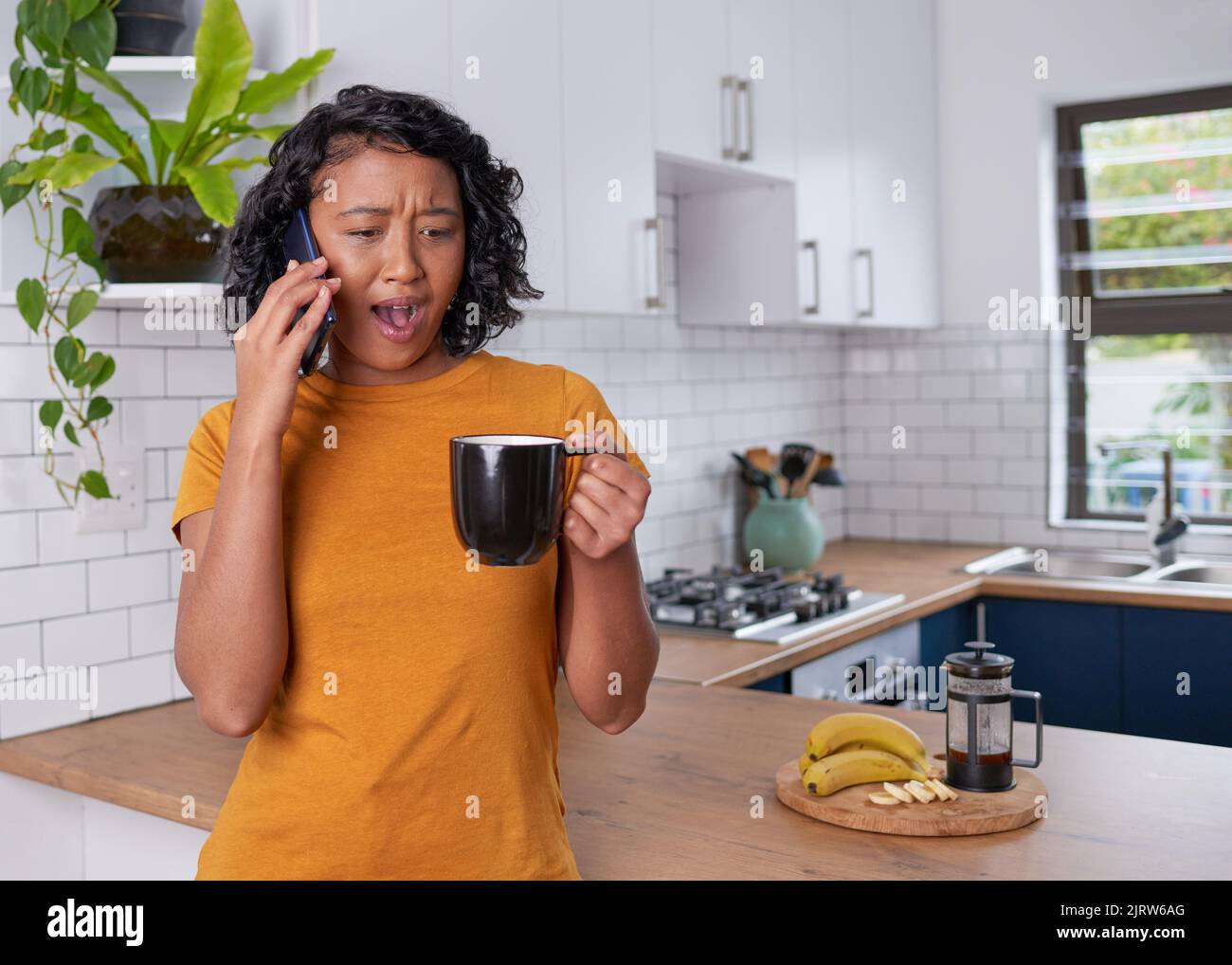Una giovane donna è sorpresa e scioccata mentre su chiamata in cucina Foto Stock
