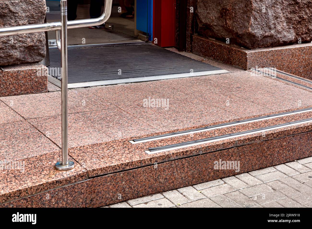ingresso con soglia in granito con gomma antiscivolo e corrimano per fare acquisti dal marciapiede pedonale attraverso il tappetino in gomma attraverso la porta in vetro, pietra Foto Stock