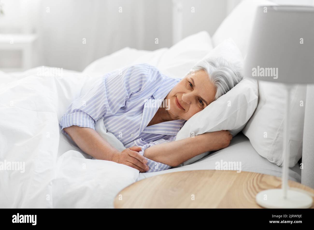 donna anziana sdraiata a letto nella camera da letto di casa Foto Stock