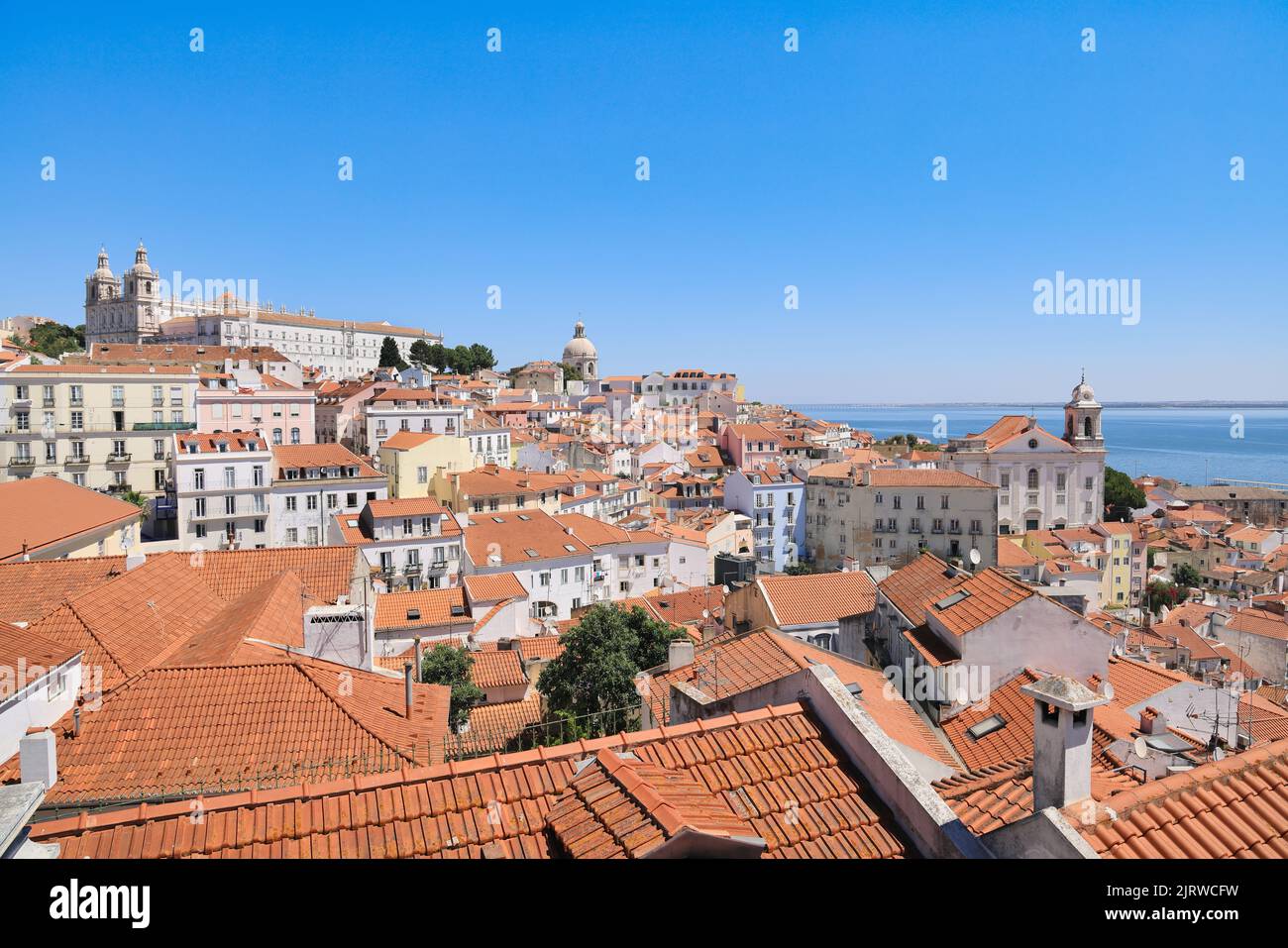 Lisbona, capitale del Portogallo. L'Alfama, il quartiere più antico di Lisbona con tetti di tegole rosse, vecchie chiese e il fiume Tago. Famosa vista da cartolina. Foto Stock