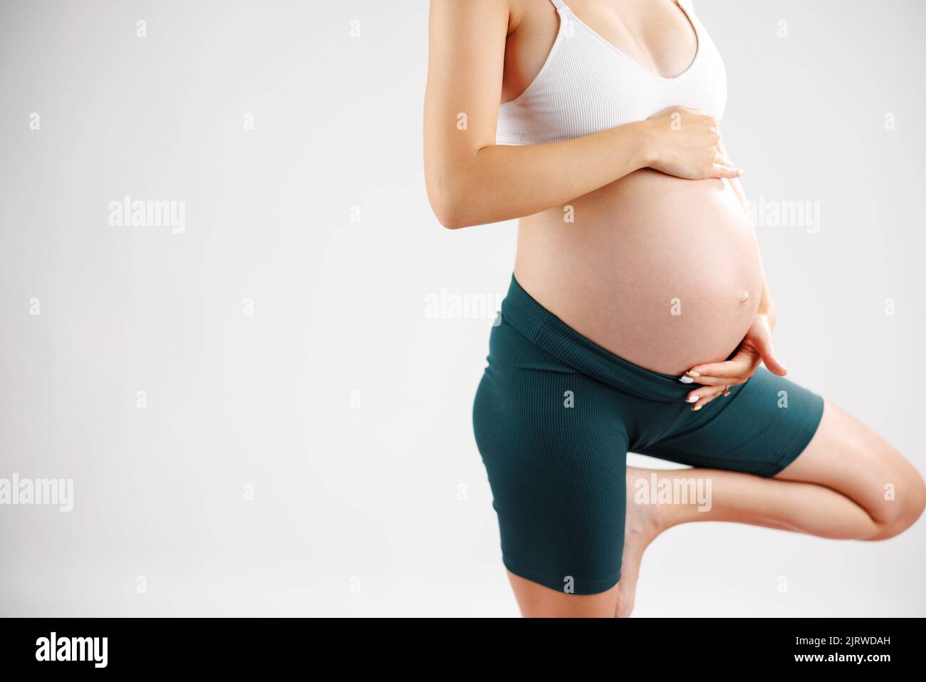 Giovane donna di yoga incinta che lavora fuori facendo la postura prenatale dell'albero, la posa di yoga. Concetto di gravidanza sana. Gesto Namaste incinta Foto Stock
