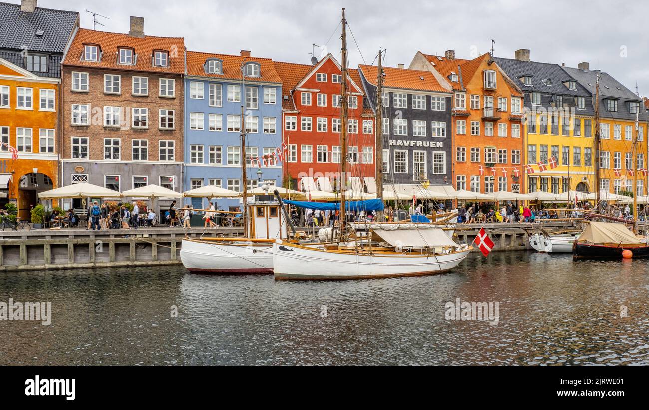 La popolare destinazione turistica di Nyhavn un'insenatura del mare fiancheggiata da colorate 17th C case caffè e bar e barche a vela - Copenhagen Danimarca Foto Stock