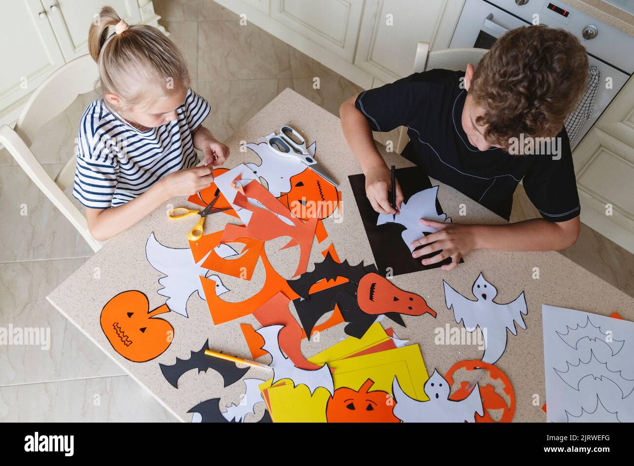 Fratello e sorella fanno artigianato da carta colorata per Halloween. Foto Stock